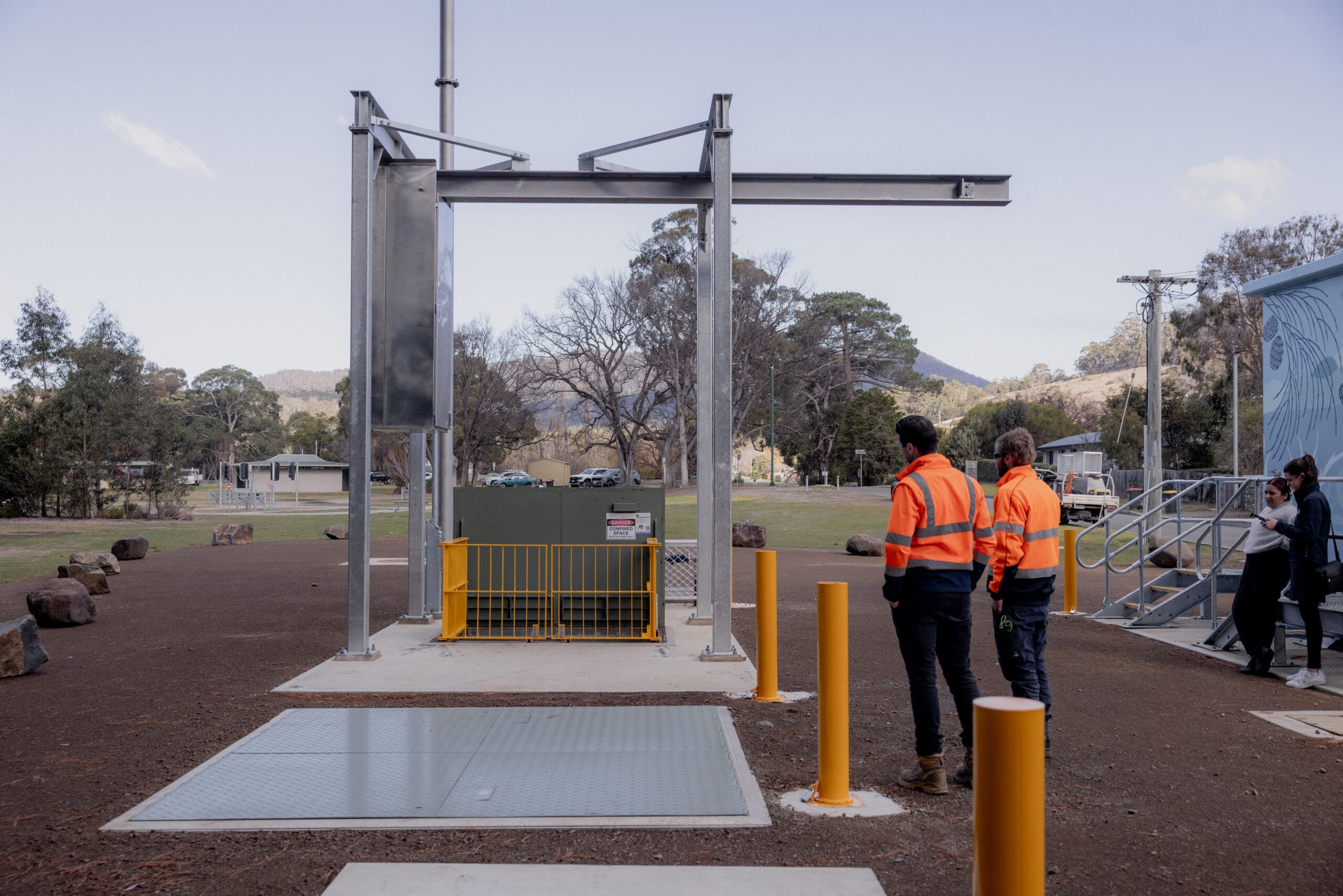 Workers observing industrial equipment in outdoor setting.