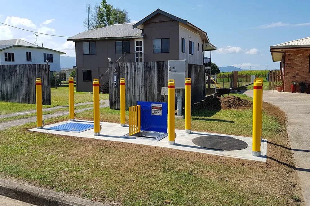 Yellow bollards surrounding water meter enclosure.